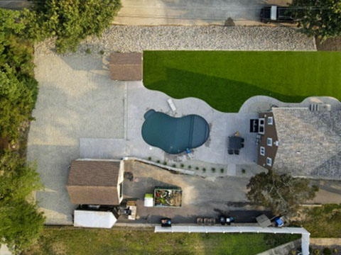 Aerial view of a backyard pool, artificial turf, stone and hardscape project
