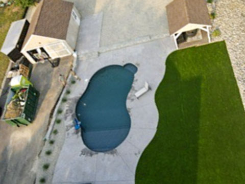 Aerial view of a completed poolside turf, paver and decorative-stone project