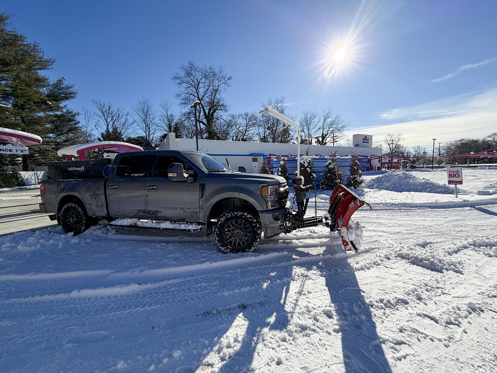 Commercial snow-plow truck clearing a business property after snowfall