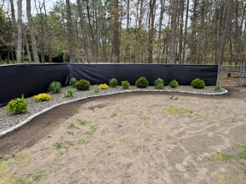Curved decorative-stone landscape bed with newly installed shrubs