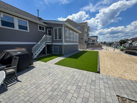 Waterfront yard with artificial turf, paver patio and decorative stone